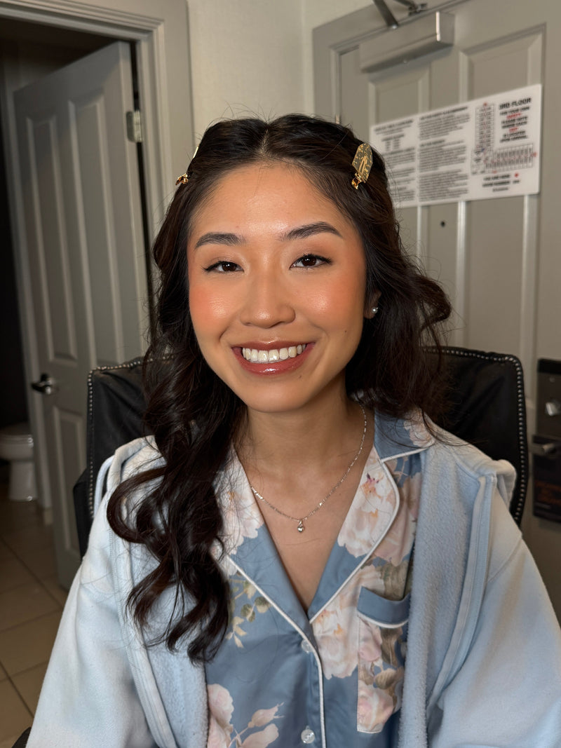 Woman in floral pajama top standing in front of a door posing for a picture after getting her makeup done
